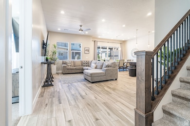 Living area featuring stairs, recessed lighting, light wood finished floors, a ceiling fan, and a chandelier
