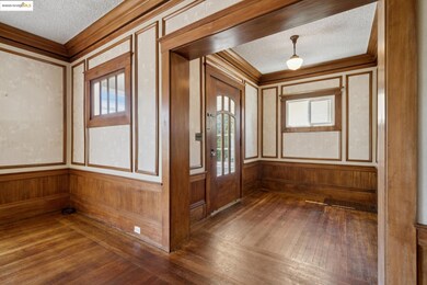 Foyer entrance with crown molding, a textured ceiling, dark wood-style floors, healthy amount of natural light, and a decorative wall