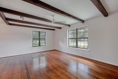 Spare room featuring beamed ceiling, wood finishe