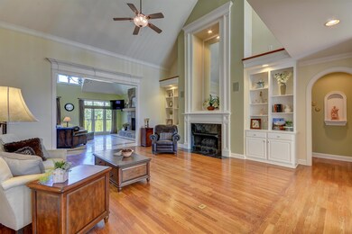 The main front living room makes a grand first impression, with its soaring 19-foot ceiling, crown molding, marble-tiled gas fireplace flanked by built-in shelving and cabinetry, and brand new hardwood flooring.