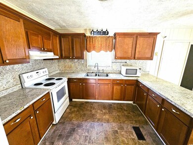 Kitchen with visible vents, under cabinet range hood, a sink, a textured ceiling, and white appliances