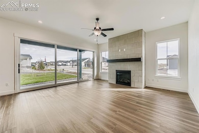 Unfurnished living room featuring light wood-type flooring, a fireplace, a ceiling fan, and recessed lighting