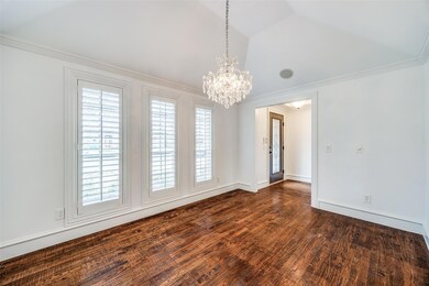 Spare room with dark wood-style floors, lofted ceiling, an inviting chandelier, ornamental molding, and baseboards
