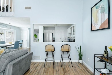 Kitchen featuring freestanding refrigerator, a kitchen bar, wood finished floors, and white cabinetry