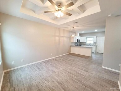 Unfurnished living room with coffered ceiling, light wood-style flooring, ceiling fan, a tray ceiling, and recessed lighting