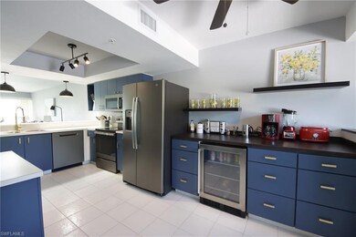 Kitchen featuring wine cooler, ceiling fan, a tray ceiling, stainless steel appliances, and sink