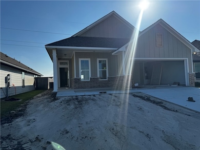 View of front facade featuring board and batten siding, roof with shingles, brick siding, and driveway