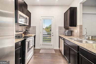 The Kitchen features Granite Countertops, Stainless Steel Appliances, Dark Wood Cabinetry, and a convenient view to the Living Room.