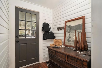 Entryway featuring dark wood finished floors, wooden walls, and vaulted ceiling