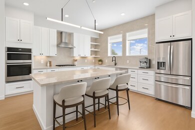 Kitchen with white cabinets, appliances with stainless steel finishes, a breakfast bar area, backsplash, and open shelves