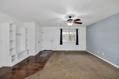 Mudroom with built in shelves, dark colored carpet, dark wood-style flooring, and ceiling fan