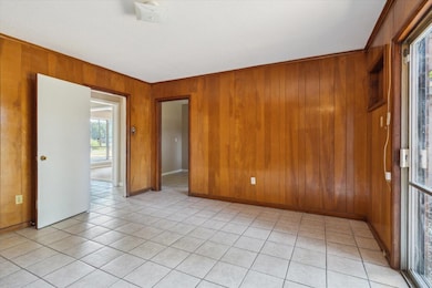 Tiled spare room featuring wooden walls