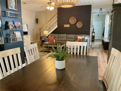 Dining room with ceiling fan, stairway, light wood-type flooring, a textured ceiling, and baseboards