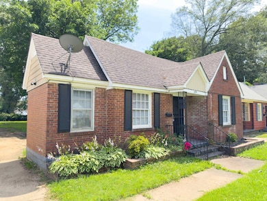 View of front facade with a shingled roof and brick siding