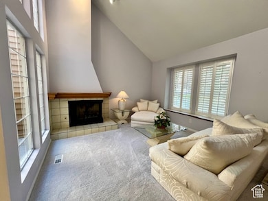 Carpeted living area featuring high vaulted ceiling and a tile fireplace
