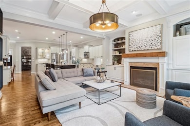 Living area featuring a chandelier, wood finished floors, ornamental molding, recessed lighting, and a glass covered fireplace