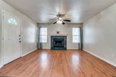 Unfurnished living room featuring a textured ceiling, ceiling fan, light wood-type flooring, and a tiled fireplace