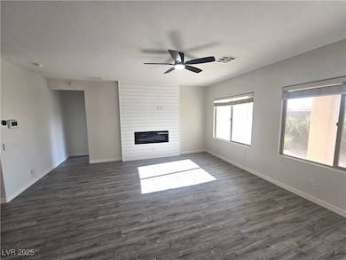 Unfurnished living room featuring a ceiling fan, d