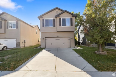 View of front of property featuring a front yard, driveway, and a garage