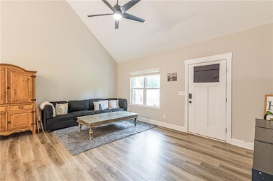 Living room with ceiling fan, high vaulted ceiling, and light wood finished floors