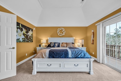 Bedroom with light colored carpet, vaulted ceiling