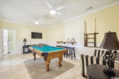 Game room with a wainscoted wall, ornamental molding, light tile patterned floors, and visible vents