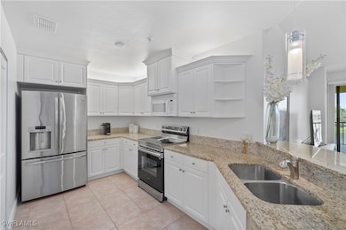 Kitchen with sink, white cabinetry, light tile pat