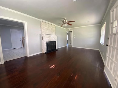 Unfurnished living room featuring a ceiling fan, wood-type flooring, a fireplace, and crown molding
