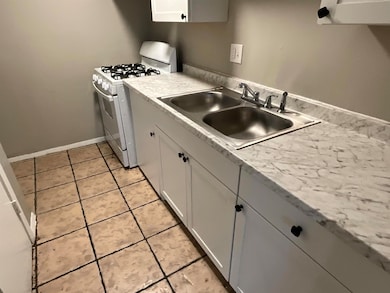 Kitchen with white range with gas cooktop, a sink, light countertops, and white cabinetry