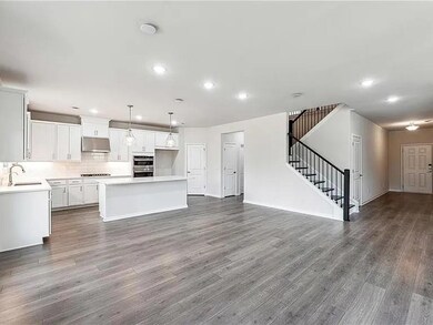 Kitchen with under cabinet range hood, double oven, a kitchen island, open floor plan, and recessed lighting