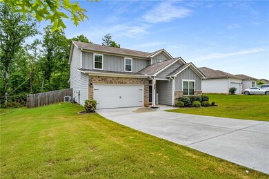 View of front facade with board and batten siding, driveway, an attached garage, central AC, and brick siding