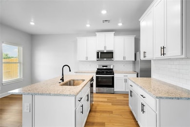 Bright kitchen with granite countertops, white shaker cabinets and subway tile backsplash.