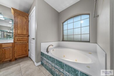 Bathroom featuring lofted ceiling, tiled bath, vanity, and tile patterned floors