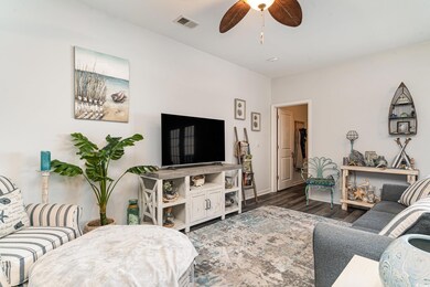 Living room featuring ceiling fan and dark hardwoo