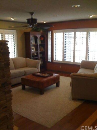 Living room features recessed lighting, ceiling fan, plantation shutters, & inlaid carpet with hardwood flooring.
