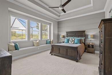 Primary Bedroom with Tray Ceiling, custom moldings, window seat, and view of pool + conservation
