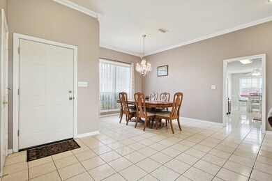 Tiled dining area with ceiling fan with notable chandelier and ornamental molding