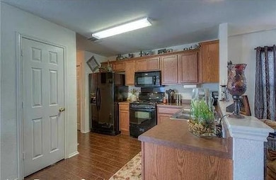 Kitchen featuring black appliances, dark wood-sty