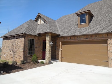 View of front of property with brick siding, roof with shingles, driveway, and a garage