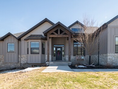 View of front of property with a front yard, stone siding, and board and batten siding