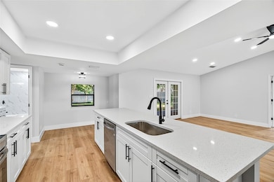 Kitchen featuring light wood finished floors, white cabinets, light stone countertops, recessed lighting, and open floor plan