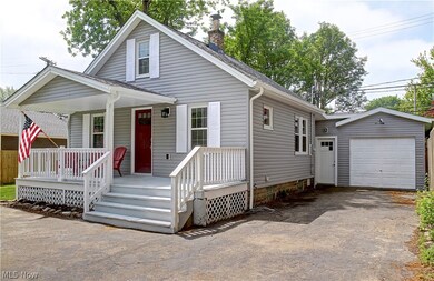 View of front of property featuring a garage, an outdoor structure, and a porch
