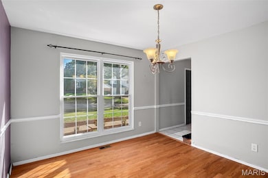 Unfurnished dining area with light wood finished floors and a chandelier