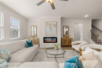 Living area featuring crown molding, stairway, ceiling fan, a glass covered fireplace, and wood finished floors