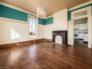 Unfurnished living room featuring an inviting chandelier, dark hardwood / wood-style flooring, and ornamental molding