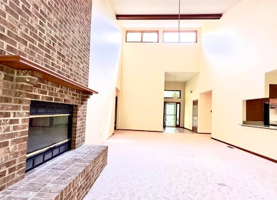 Unfurnished living room with a towering ceiling, a fireplace, and carpet flooring