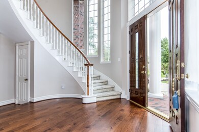 You are ushered into a grand entry hall with real wood floors and a sweeping curved staircase.