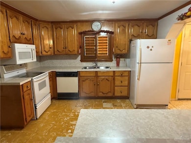 Kitchen featuring white appliances, brown cabinets, light countertops, and light floors.