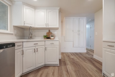 Kitchen with dishwasher, white cabinets, light wood finished floors, light stone counters, and recessed lighting