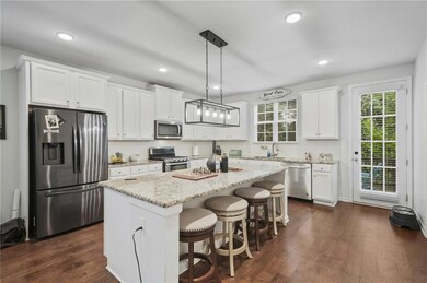 Kitchen with stainless steel appliances, a kitchen island, white cabinetry, a breakfast bar, and light stone countertops